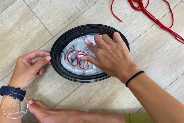 Harry Potter Remembrall Positive Mindset Activity - overhead view of the strip of yarn being soaked in a bowl with a generous amount of glue