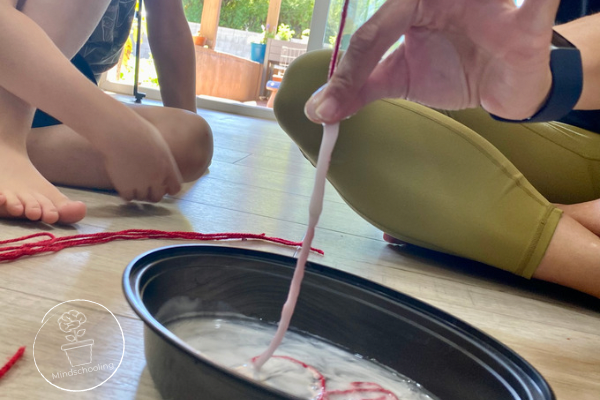 Harry Potter Remembrall Positive Mindset Activity - side view of the strip of yarn being squeezed over a bowl releasing excess glue off of the string