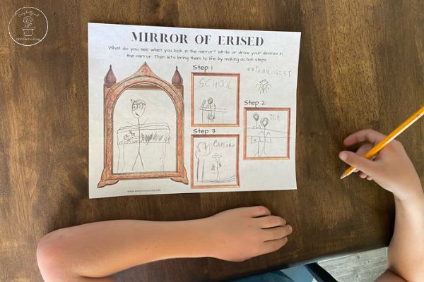 Harry Potter Mirror of Erised Activity - An overhead picture of a child sitting at the table, holding a pencil, after completing the printable worksheet