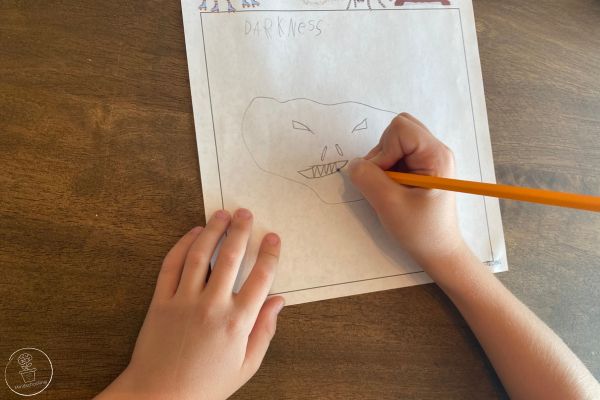 A child drawing a fear of darkness onto a worksheet