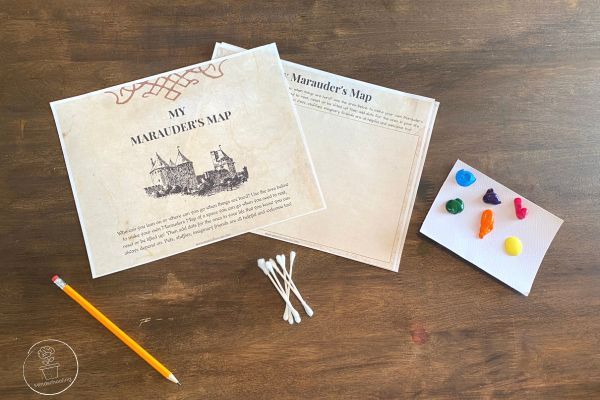 Various supplies including a pencil, Q-tips, the Marauder's Map printable and a card with various colors of paint to choose from, all laid out on a table