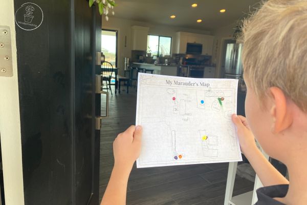 Point of view is from behind a child holding the Harry Potter Maurader's Map printable which shows people and places of safety. The child is also examining the room in front of him
