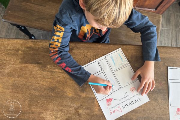 An overhead view of a child completing a brain dump printable, using a color pencil